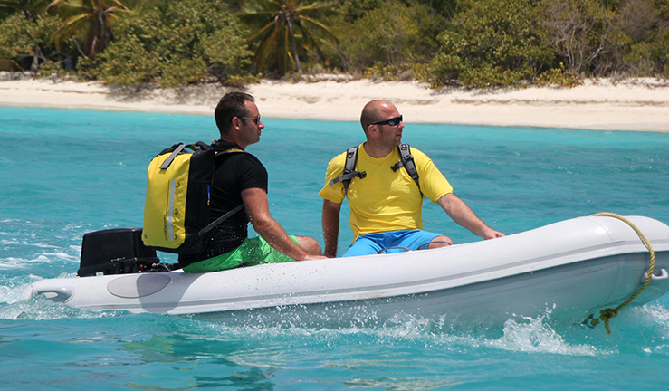 Two men in a rib, one carrying overboard bag on shoulder