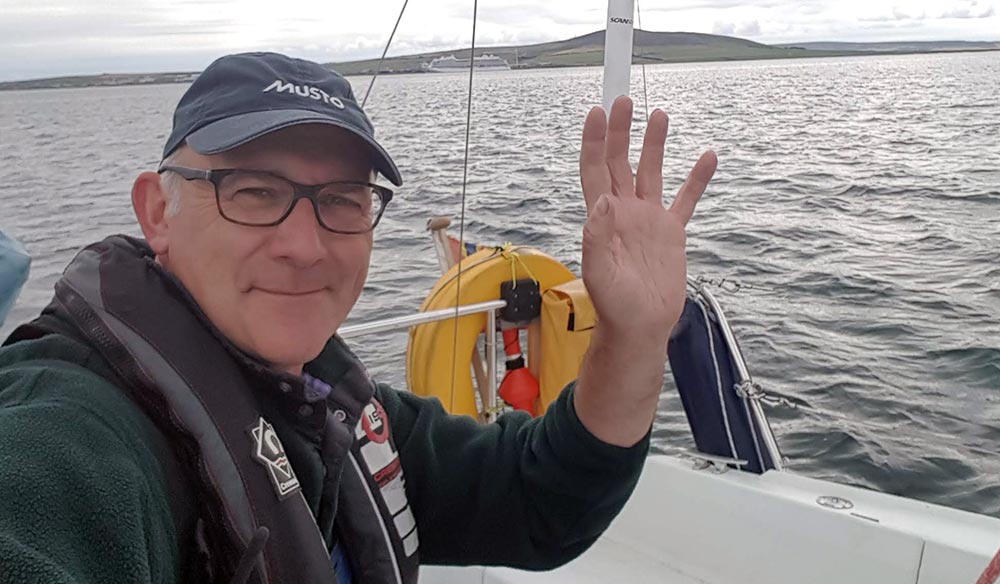 mid shot of Stephen waving while on sailing yacht