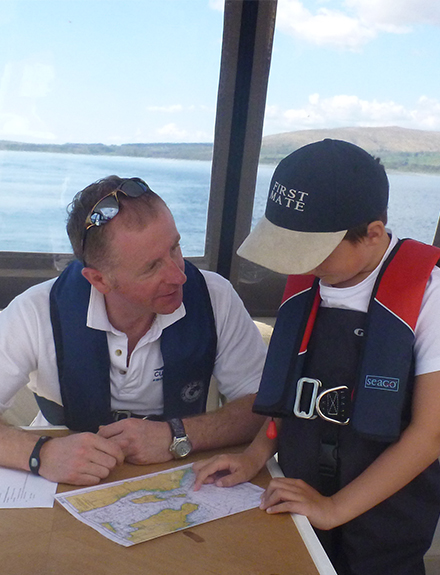 Instructor and young boy looking at charts on motor cruiser